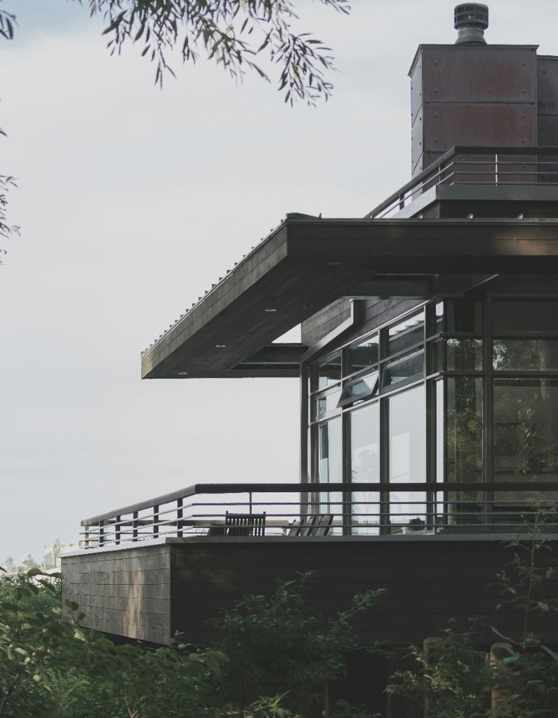 A cantilevered steel and glass structure amid dense foliage
