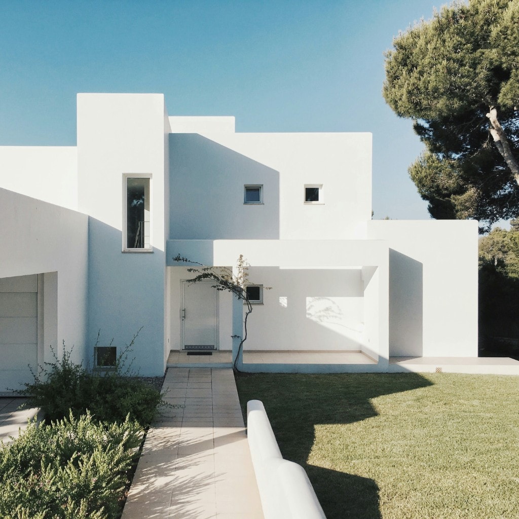 A white minimalist residential volume under open sky